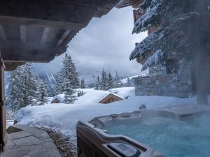 una vasca idromassaggio coperta di neve accanto a un edificio di Chalet à Courchevel avec piscine, jacuzzi et vue panoramique - FR-1-613A-13 a Courchevel