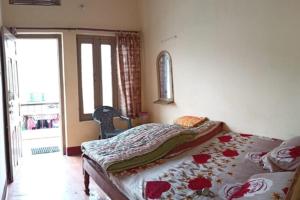 a bedroom with a bed with a floweredspread on it at Purohit Lodge B&B by StayApart in Gupta Kāshi
