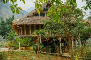 una casa con tetto di paglia in una foresta di Mai Chau Villas a Mai Châu