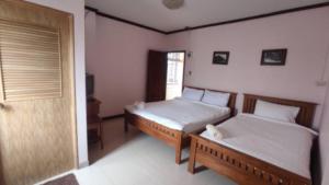 a bedroom with two beds and a door and a window at บ้านบำรุงสุข in Chiang Khan