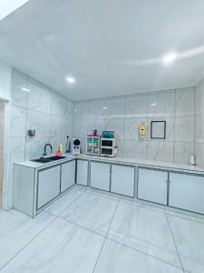 a large kitchen with white tile walls and a sink at Zzora Home 28 in Alor Setar