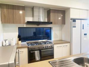Una cocina con estufa y fregadero. en Kellyville Adorable 5 Br Home near Parks & Shops, en Kellyville