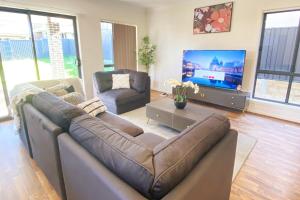 Una sala de estar con un sofá y un televisor de pantalla plana. en Kellyville Adorable 5 Br Home near Parks & Shops, en Kellyville