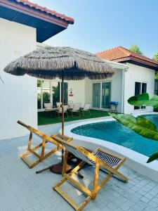 a pool with a straw umbrella and chairs next to a house at Majestic Residence Seaside villa Private beach in Pattaya South +46 photos