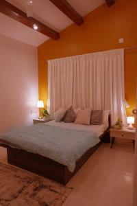 a bedroom with a large bed with a white curtain at YOLO villa in Pirangut