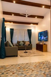 a living room with a couch and a tv at YOLO villa in Pirangut