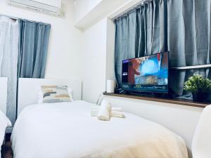 1 dormitorio con 2 camas y TV de pantalla plana en una ventana en Nishiwaseda, en Tokio