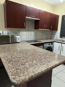 a kitchen with a granite counter top with a microwave at Jackal Cosy One Bed in Roodepoort