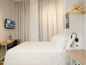 una camera d'albergo con un letto bianco e una scrivania di Apê Santos Praia do Gonzaga a Santos