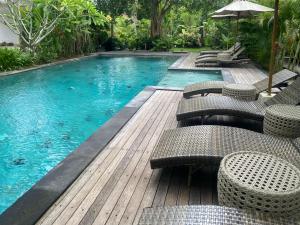 a pool with chairs and an umbrella on a wooden deck at Kulkul Bungalow in Nusa Penida