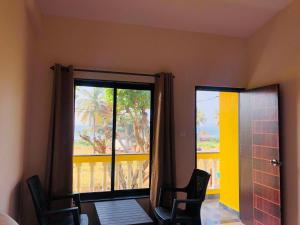 a room with two chairs and a large window at Nelis Guest House in Bogmalo