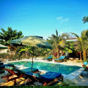 een zwembad met stoelen en een parasol ernaast bij Diana Place in Paje
