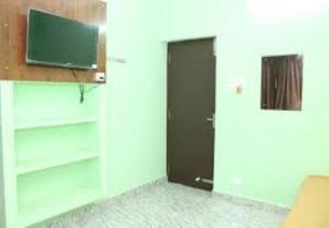 a room with a door and a television on a wall at Villa Saravana in Puducherry