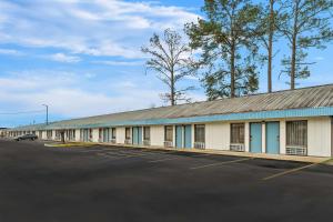 a building with a lot of windows and a parking lot at Rodeway Inn & Suites in Brookhaven