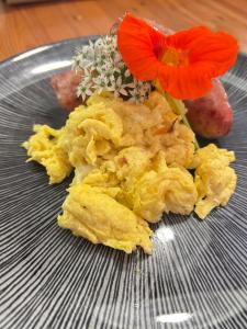 un piatto con uova strapazzate e fiori rossi sopra di Glen Eden Lodge a Lidgetton