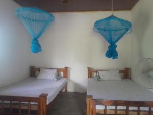two beds in a room with blue curtains at The Happy House Nature Retreat in Talakolawela