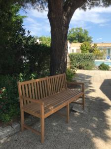 a wooden bench sitting next to a tree at Le Petit Bois in Sainte-Marie-de-Ré