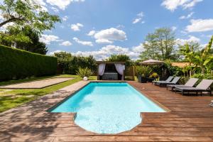 - une piscine dans un jardin avec une terrasse en bois dans l'établissement Gîte & Chambres d'Hôtes - Le Petit Bali, à Saint-Pandelon