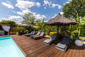 une terrasse avec des chaises et un parasol et une piscine dans l'établissement Gîte & Chambres d'Hôtes - Le Petit Bali, à Saint-Pandelon 38 autres photos