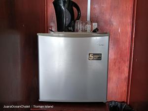 a small refrigerator sitting next to a wooden wall at Juara Ocean Chalet in Kampong Juara