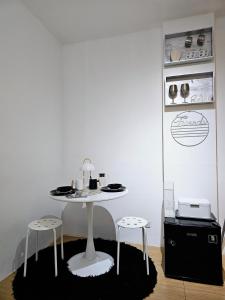 une table blanche et deux tabourets dans une pièce dans l'établissement Comfort Stay at Intramuros by IN CAFEBAR, à Manille