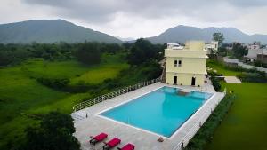 an overhead view of a swimming pool with mountains in the background at Alcor Kumbhalgarh - the family getaway in Kelwāra