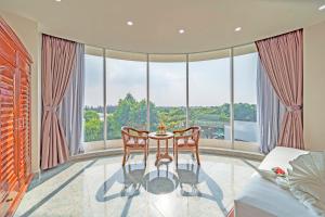 1 dormitorio con mesa y sillas frente a grandes ventanas en Venus Hotel, en Ho Chi Minh