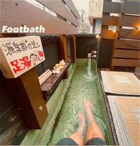 a person in a pool with their feet in a hot tub at 源泉掛け流し温泉付きの宇佐美貸切宿 お宿 喜喜哀楽 Oyado Kikiairaku #IG2 in Ito