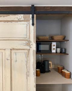 une cuisine avec un four micro-ondes sur une étagère dans l'établissement Maison Honorine, à Saint-Geniès
