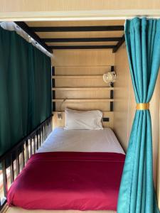 a bed in a room with a window and a curtain at Plearn Phuket Boutique Hostel in Ban Lo Long
