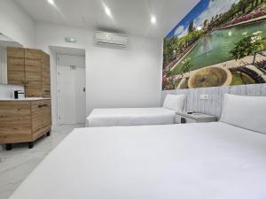 a bedroom with two beds and a painting on the wall at Nueva PENSION CIBELES in Córdoba