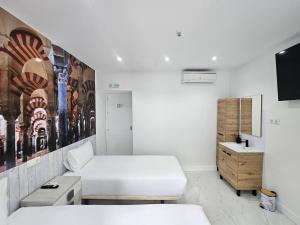 a white room with two beds and a sink at Nueva PENSION CIBELES in Córdoba