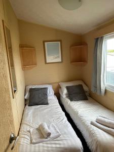 two beds in a small room with a window at Newquay Bay Porth Caravan - 3 Bed in Newquay