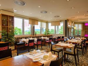 uma sala de jantar com mesas, cadeiras e janelas em Mövenpick Hotel Egerkingen em Egerkingen