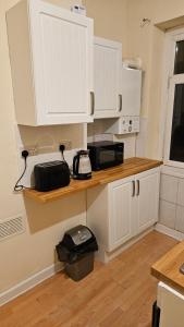 a kitchen with white cabinets and a counter with a microwave at Entire 2 Bedroom Apartment City Centre & Stadium in Cardiff