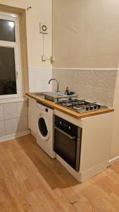a kitchen with a stove and a washing machine at Entire 2 Bedroom Apartment City Centre & Stadium in Cardiff