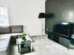 un soggiorno con un divano e una TV di Just Stay 2 a Warrington
