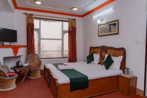 a bedroom with a bed and a tv and a window at Hotel Victoriya Palace,Mcleod Ganj in McLeod Ganj