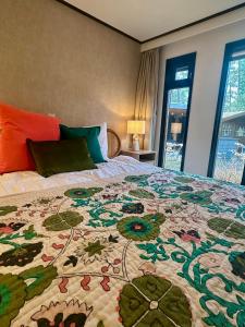 a bed with a colorful quilt on it in a bedroom at StayatSas Tiny House Pippa in de bossen op de Veluwe in Doornspijk +101 photos