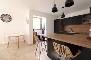a kitchen with a counter and chairs and a clock at Sublime Appartement avec Parking Privé à Ajaccio in Ajaccio
