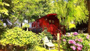 RivièreLa Gypsy Caravan的鲜花盛开的花园中红色小屋,配有长凳