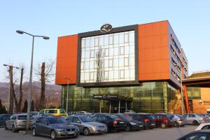 a parking lot with cars parked in front of a building at Hotel Zenica in Zenica