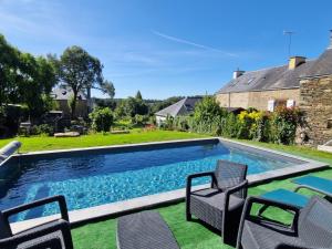 a swimming pool with chairs and a yard at La Moutonne des Landes de Lanvaux in Saint-Jacut-les-Pins