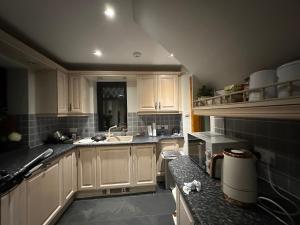 una cucina con mobili bianchi e un lavandino di Ann Cottage Retreat in Aberdeen ad Aberdeen