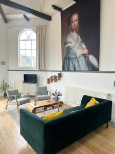a living room with a green couch and a painting at Himelsk in Koudum