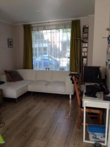 a living room with a white couch and a window at Nice and cosy house close Amsterdam and airport in Badhoevedorp