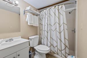 a bathroom with a toilet and a shower curtain at Oceanfront Inn Suite #6- King Bed in Fort Pierce