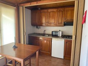a kitchen with wooden cabinets and a table and a microwave at Quinta da Memória Village in Vimieiro