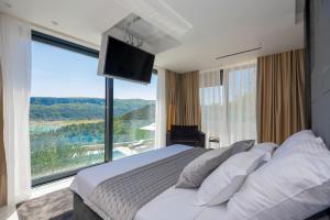 a bedroom with a large bed with a large window at Luxury Villa Karmen with pool & spa zone in Ričice +133 photos