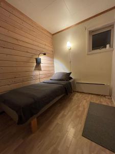 a bedroom with a bed with a wooden wall at Homestay - Central Hammerfest in Hammerfest